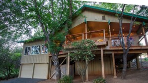 A two-story wooden cabin with a balcony, surrounded by trees. - Rustic Charm Meets Modern Comfort (Groveland)