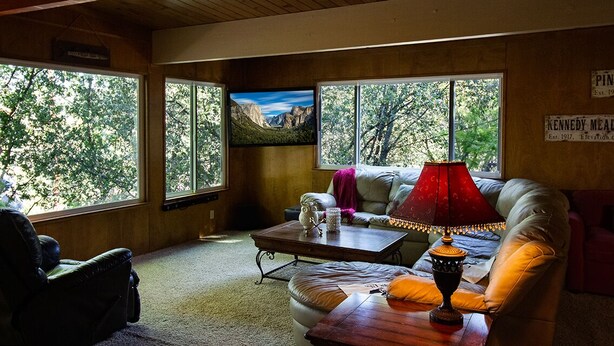 A cozy room with large windows, a comfortable sofa, a coffee table, and a television. - Rustic Charm Meets Modern Comfort (Groveland)