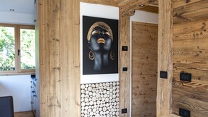 Een modern interieur met een houten wand, een zwart kunstwerk en een wand van boomstammen.