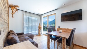 Een moderne woonkamer met een houten eettafel, een bank en een beeld.