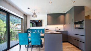 Una cocina moderna con comedor, ventanas amplias y vistas a un área boscosa.