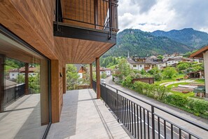 A balcony with a wooden railing overlooking a village and mountains. - 195B Apartments LaBar (Ortisei)