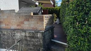 A stone wall, a metal railing, and a pathway leading to a building with a tiled roof. - Ferienwohnung Heidi (Rielasingen-Worblingen)
