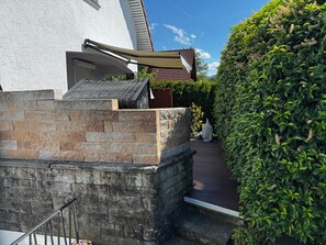 A stone wall, a metal railing, and a pathway leading to a building with a tiled roof. - Ferienwohnung Heidi (Rielasingen-Worblingen)