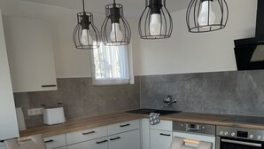 A modern kitchen with a wooden table, a Bosch oven, and pendant lights. - Ferienwohnung Heidi (Rielasingen-Worblingen)