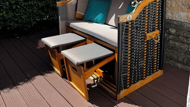 A wooden deck with a covered seating area featuring a cushioned bench and a table. - Ferienwohnung Heidi (Rielasingen-Worblingen)