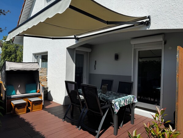 A patio with a table and chairs, a covered seating area, and a sliding glass door.