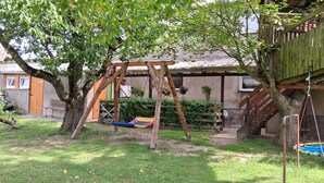 Ein hölzernes Schaukelgestell in einem Garten mit einem Haus im Hintergrund.