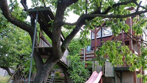 Ein Baumhaus mit Rutsche, das an einem Baum im Garten befestigt ist.
