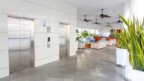 A spacious lobby with a modern design, featuring a seating area with sofas and armchairs, a reception desk, and two elevators. - NEW Apartment Frente a la Playa Bocagrande (Cartagena de Indias)