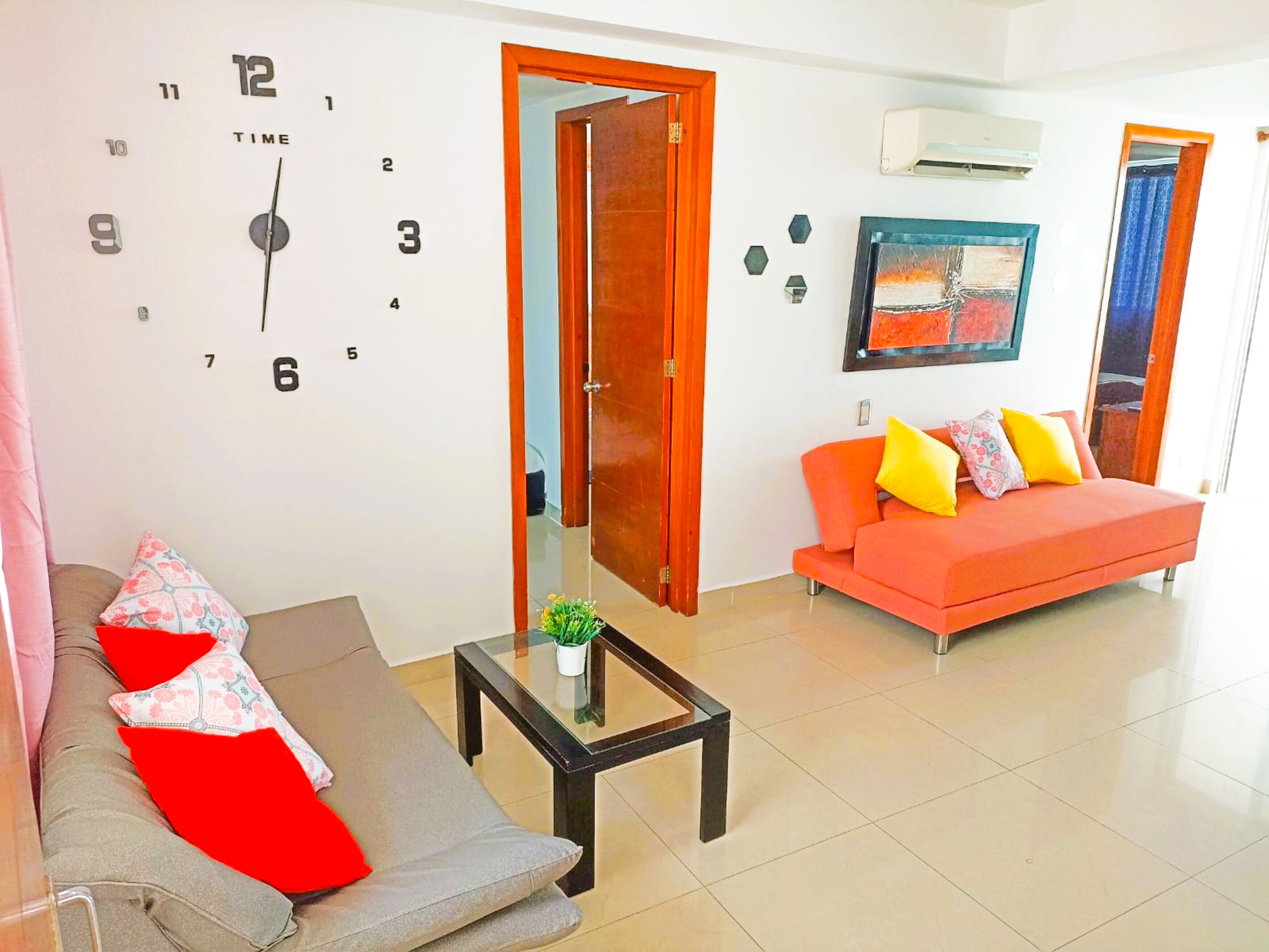 A living room with a sofa, a coffee table, and a wall clock.