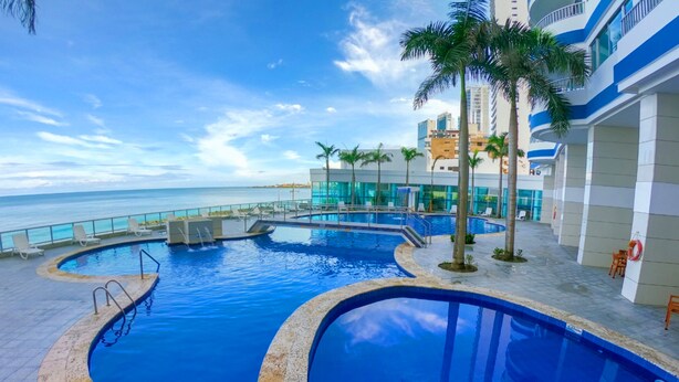 A pool area with multiple swimming pools, palm trees, and a view of the ocean. - NEW Apartment Frente a la Playa Bocagrande (Cartagena de Indias)