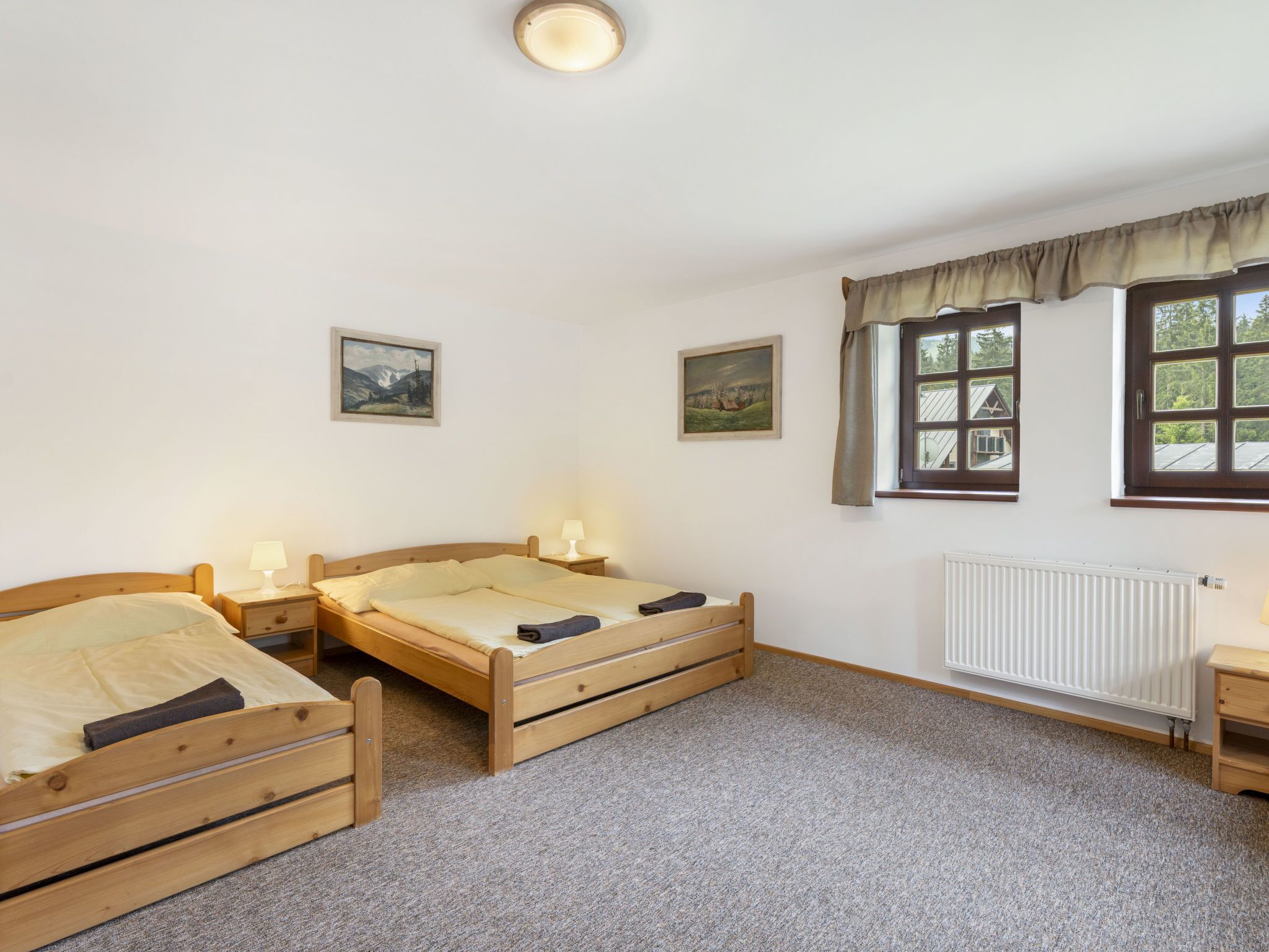 Ein Schlafzimmer mit zwei hölzernen Betten, einem Heizkörper und zwei Nachttischen mit Lampen.