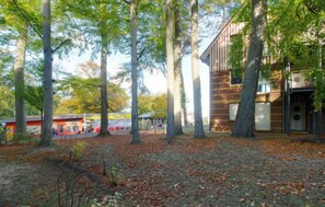 A view of a terraced outdoor area with trees and a building in the background. - Jeschek by Interhome (Koserow)