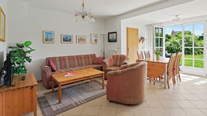 A living room with a sofa, armchairs, a coffee table, a TV, and a plant. - Achterwasser App. 13 by Interhome (Zempin)