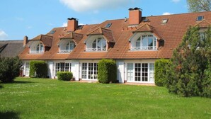 A row of traditional houses with multiple chimneys, large windows, and a well-maintained lawn. - Achterwasser App. 13 by Interhome (Zempin)