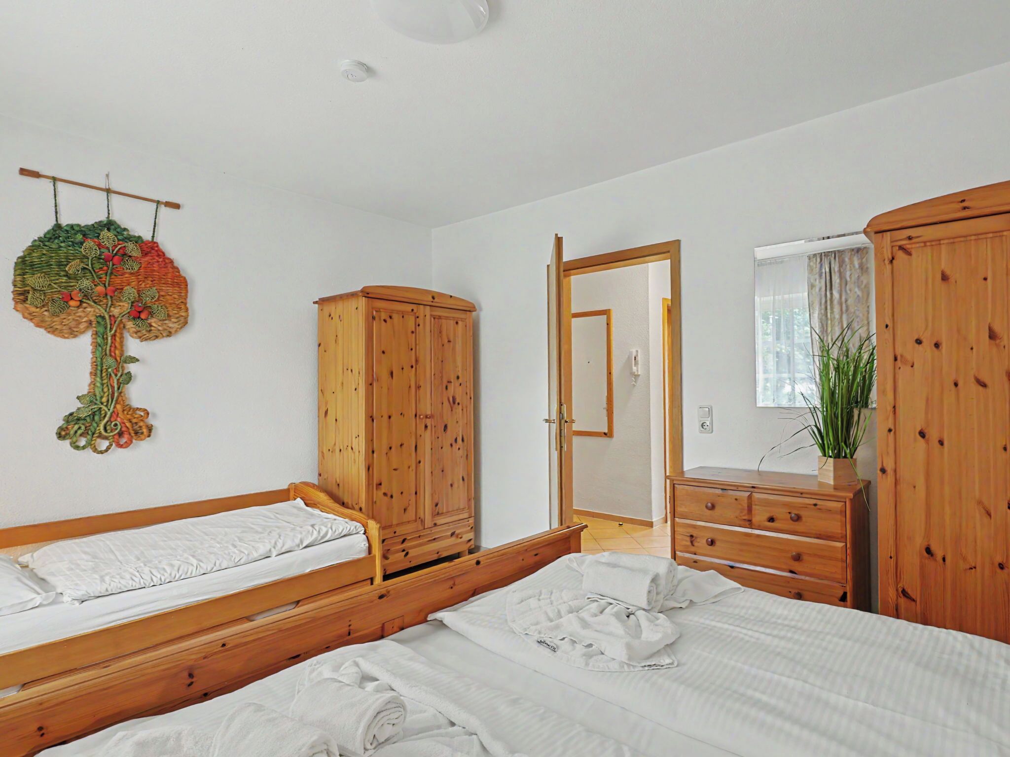 A bedroom with two wooden beds, a wardrobe, a mirror, and a hanging decoration.