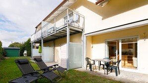 En boligejendom med balkon, terrasse med liggestole, spiseplads og garage.