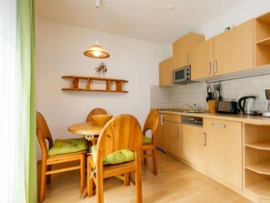 Une cuisine compacte dotée de meubles en bois, d’un four à micro-ondes, d’un évier et d’un coin repas avec une table et des chaises.