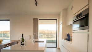 A modern kitchen with a central island, stainless steel appliances, and a view to the outside. - One with terrace and dune view by Interhome (Blankenberge)