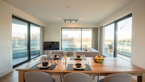 A modern dining area with a large table set for four, large windows, and a view of the outside. - One with terrace and dune view by Interhome (Blankenberge)