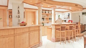 A wooden bar area with a curved counter, multiple stools, and a tiled floor. - Apartment Top 4 by Interhome (Ischgl)