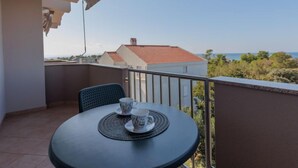Un balcón con una mesa y dos tazas, con vista a una zona residencial y al mar.