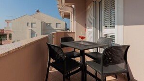 A balcony with a table and chairs, a drink, and a view of neighboring buildings. - Apartment Irena by Interhome (Privlaka)