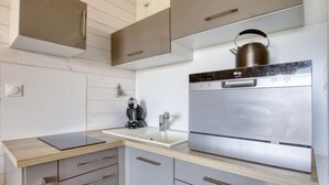 A modern kitchen with a stainless steel refrigerator, a kettle on top, and a coffee machine.