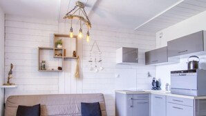 A modern kitchen with grey cabinets, a stainless steel refrigerator, and a hanging light fixture.