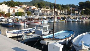 A marina with several boats docked, surrounded by residential buildings and a hilly landscape.