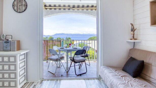 A balcony with a table and chairs, a sofa, a clock, and a shelf with a decorative item.