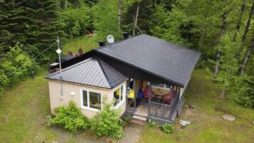 Une petite cabane avec un toit en métal, entourée d’une forêt dense.