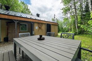 Eine rustikale Holzhütte mit einem Metalldach, einem Tisch mit Stühlen und einer Holzterrasse.