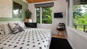 Una camera da letto con un letto, una finestra grande, una televisione e una pianta.