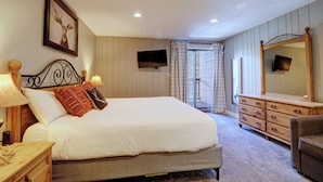 Ein Schlafzimmer mit Bett, Nachttischen, einem Schminktisch und einem Spiegel sowie einem Fernseher.