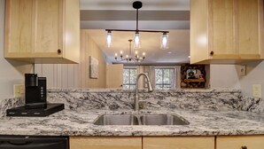 A kitchen with wooden cabinets, a granite countertop, a stainless steel sink, a coffee maker, and a dishwasher. - Dog Friendly Incredible Ski-in/Ski-out Condo, Great Views, CM325/CM329 (Copper Mountain)