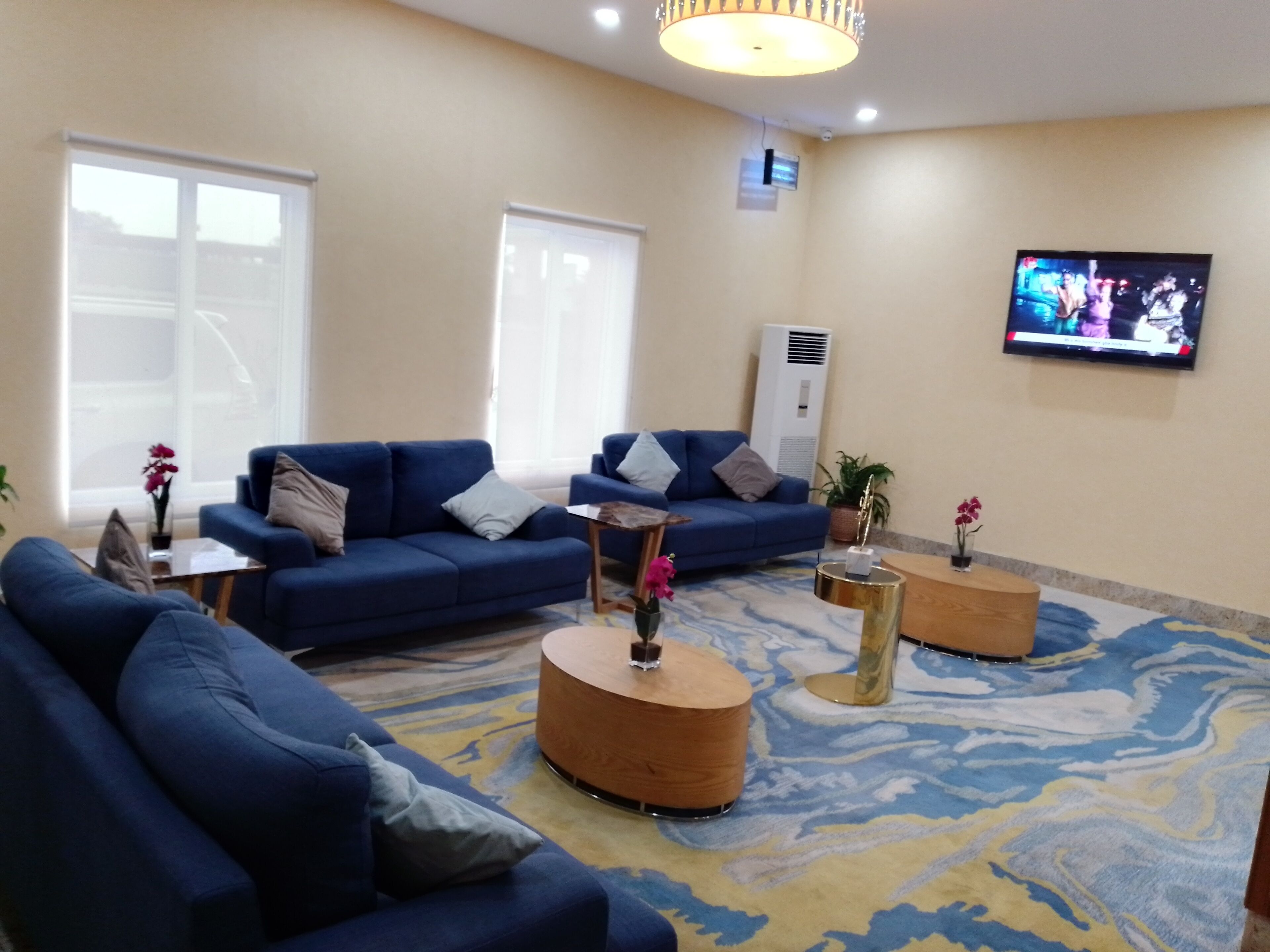 Una sala de estar moderna con sofás azules, una mesa de centro y un televisor montado en la pared.