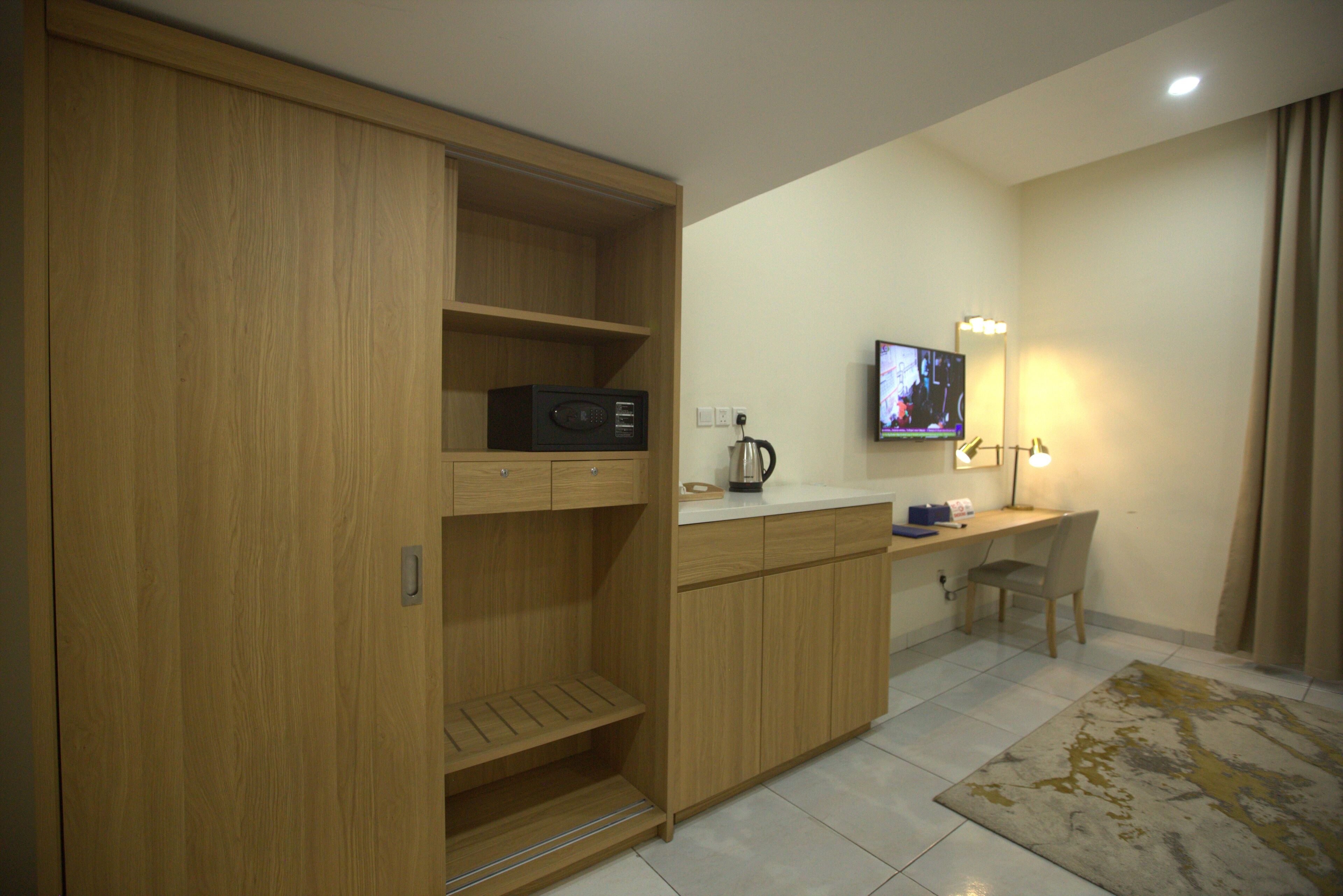 Una cocina compacta con microondas, cafetera y un televisor de pantalla plana sobre un mueble de madera.