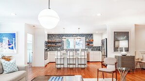 Una cocina moderna con armarios blancos, una isla central y un comedor con taburetes de bar.