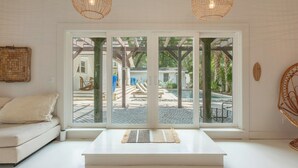 Una sala de estar moderna con un sofá, una mesa de centro y vistas a un patio exterior a través de puertas de vidrio.