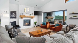 A spacious living room with a fireplace, modern furniture, and a large window offering a view of the outdoors. - Lake View|Pools·Sauna·Hot Tub|Game&Theater Room·24 (Branson)
