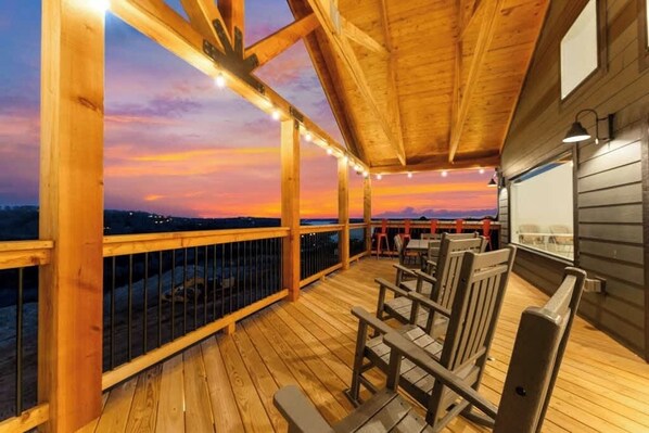 A wooden deck with a sunset view, wooden railings, and a table with chairs.