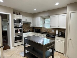 A modern kitchen with white cabinetry, stainless steel appliances, and a central island. - Cozy 3bdrm 2bath house for families w/ small kids & infants near White Rock Lake (Dallas)