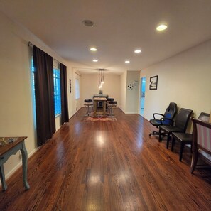 A spacious room with a long wooden floor, a dining table with chairs, and a seating area with chairs. - Cozy 3bdrm 2bath house for families w/ small kids & infants near White Rock Lake (Dallas)