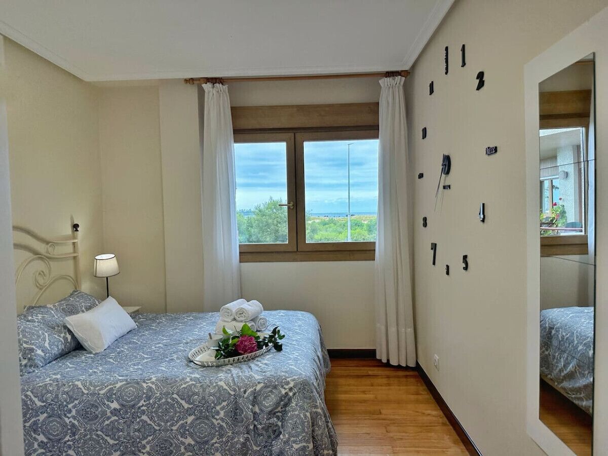 A bedroom with a bed, a bedside table with a lamp, a window with curtains, and a wall with numbers.