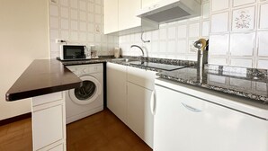 Eine kompakte Küche mit Waschmaschine, Mikrowelle und Spüle inklusive modernem Wasserhahn.