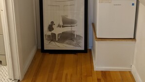 A corner of a room with a framed black and white photograph, a white refrigerator, and a wooden clothes rack with hangers. - Trailside Inn (Mount Stewart)