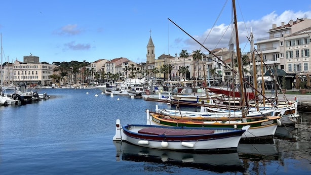 A marina with several colorful boats docked, a prominent tower in the background, and buildings along the waterfront. - A 5 du Centre et des Plages, Maison Avec Jacuzzi (Sanary-sur-Mer)