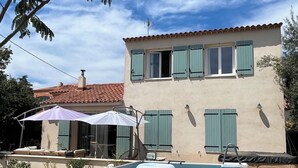 A swimming pool with inflatable toys, a covered area, and a building with green shutters. - A 5 du Centre et des Plages, Maison Avec Jacuzzi (Sanary-sur-Mer)